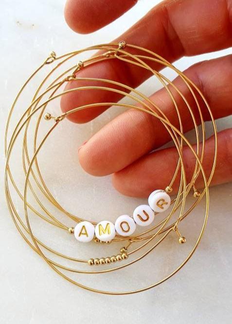7 bracelets dorés en acier inoxydable avec perles blanches - Semainier Amour, élégant et tendance.