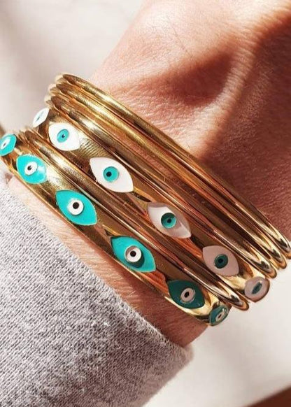 Ajoutez une touche bohème et protectrice à votre look avec ce jonc doré, élégant et symbolique. Confectionné en acier inoxydable, il est orné de 7 œillets protecteurs sur la face avant, chacun représentant un symbole d'œil grec pour éloigner les énergies négatives et attirer la protection.